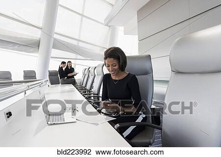 Businesswoman using cell phone in conference room View Large Photo Image Stock Image - Businesswoman using cell phone in conference room. Fotosearch