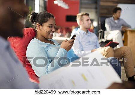 Businesswoman using cell phone in office lounge View Large Photo Image Stock Photo - Businesswoman using cell phone in office lounge. Fotosearch