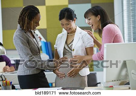 Businesswomen admiring pregnant co-worker's stomach View Large Photo Image Stock Image - Businesswomen admiring pregnant co-worker's stomach. Fotosearch