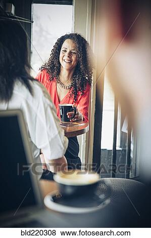 Stock Photo - Businesswomen drinking coffee in cafe. Fotosearch