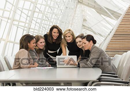 Stock Image - Busy businesswomen using laptop in meeting. Fotosearch