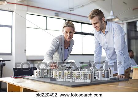 Stock Image - Caucasian architects examining architectural model in office. Fotosearch