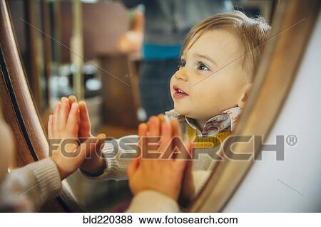 Stock Photo - Caucasian baby boy standing at mirror. Fotosearch