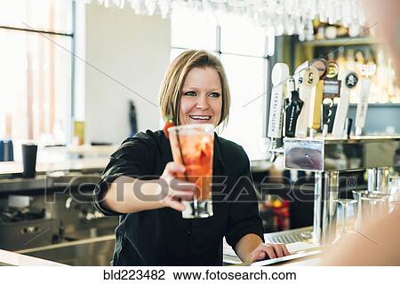Stock Image - Caucasian bartender serving cocktail. Fotosearch