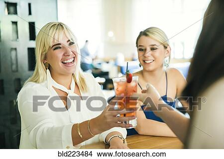 Picture - Caucasian bartender serving cocktail to women. Fotosearch