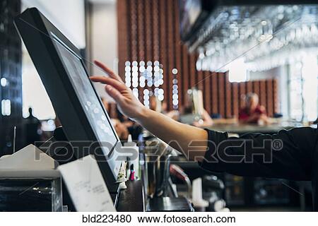 Stock Image - Caucasian bartender using computer. Fotosearch