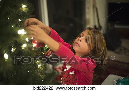 Stock Image - Caucasian boy hanging ornament on Christmas tree. Fotosearch