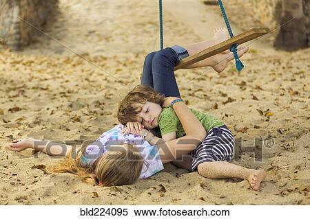 Stock Photography - Caucasian boy laying on chest of sister at beach. Fotosearch