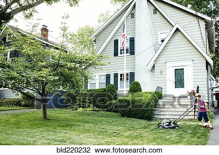Stock Image - Caucasian boy mowing front lawn. Fotosearch