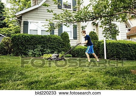 Stock Image - Caucasian boy mowing front lawn. Fotosearch
