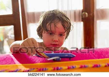 Stock Image - Caucasian boy playing with toy airplane. Fotosearch