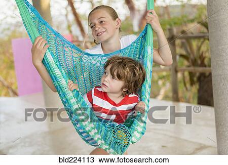 Caucasian boy sitting in hammock held by sister View Large Photo Image Stock Image - Caucasian boy sitting in hammock held by sister. Fotosearch