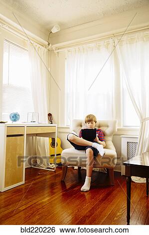 Stock Photograph - Caucasian boy using digital tablet in living room. Fotosearch