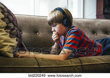 Caucasian boy using digital tablet on sofa View Large Photo Image Stock Photo - Caucasian boy using digital tablet on sofa. Fotosearch
