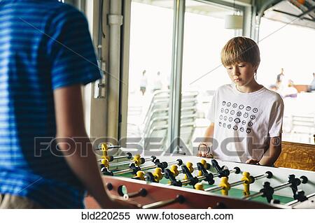 Stock Photography - Caucasian brothers playing foosball. Fotosearch