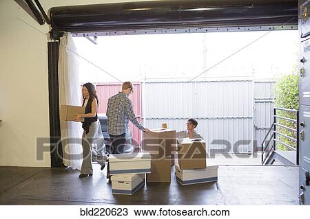 Stock Image - Caucasian business people unpacking boxes in new office. Fotosearch