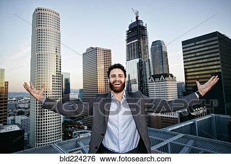 Stock Photograph - Caucasian businessman celebrating on urban rooftop. Fotosearch
