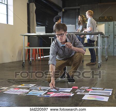 Stock Photo - Caucasian businessman examining paperwork on office floor. Fotosearch