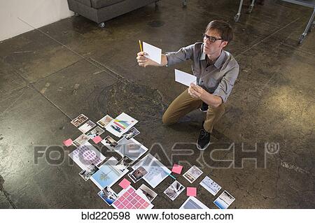 Stock Photo - Caucasian businessman examining paperwork on office floor. Fotosearch