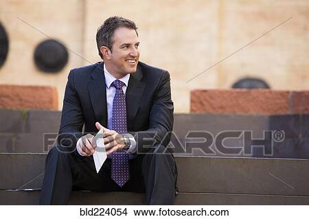 Caucasian businessman sitting on staircase holding paperwork View Large Photo Image Picture - Caucasian businessman sitting on staircase holding paperwork. Fotosearch