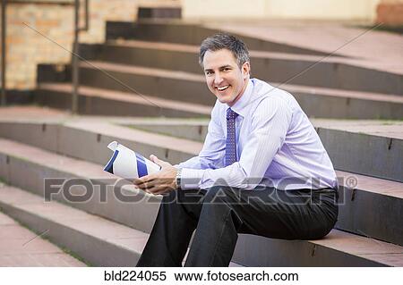 Caucasian businessman sitting on staircase holding paperwork View Large Photo Image Stock Photography - Caucasian businessman sitting on staircase holding paperwork. Fotosearch