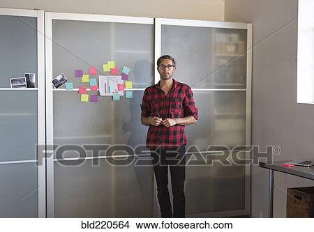 Caucasian businessman standing by cabinet in office View Large Photo Image Picture - Caucasian businessman standing by cabinet in office. Fotosearch