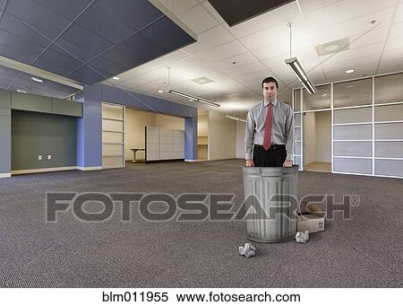 Caucasian businessman standing with garbage cans in empty office View Large Photo Image Stock Photography - Caucasian businessman standing with garbage cans in empty office. Fotosearch