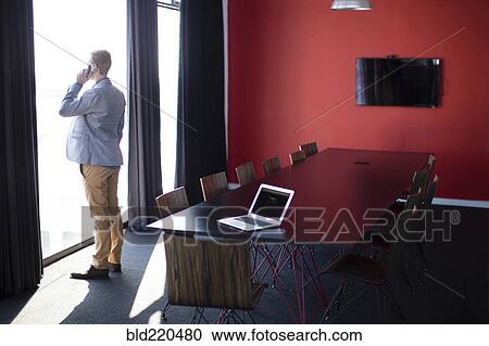 Stock Image - Caucasian businessman talking on cell phone in conference room. Fotosearch