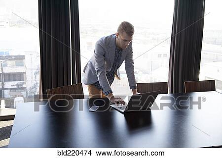 Picture - Caucasian businessman using laptop in conference room. Fotosearch