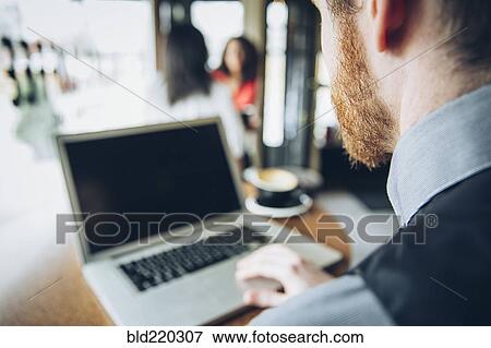 Stock Photo - Caucasian businessman using laptop in cafe. Fotosearch