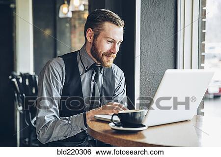 Stock Photograph - Caucasian businessman using laptop in cafe. Fotosearch