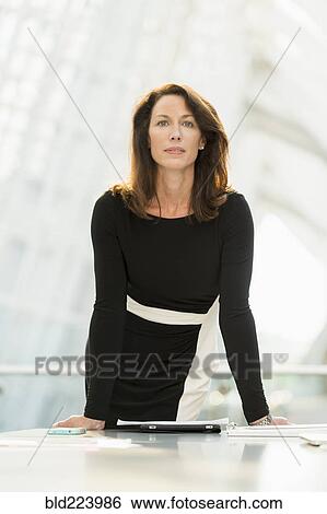 Caucasian businesswoman leaning on table View Large Photo Image Stock Photograph - Caucasian businesswoman leaning on table. Fotosearch