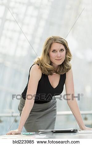 Stock Photography - Caucasian businesswoman leaning on table. Fotosearch