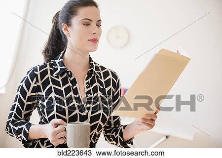Stock Image - Caucasian businesswoman reading paperwork in file folder. Fotosearch