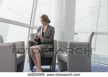 Caucasian businesswoman sitting in armchair using cell phone View Large Photo Image Stock Image - Caucasian businesswoman sitting in armchair using cell phone. Fotosearch