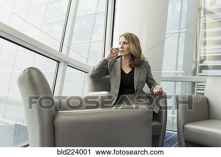 Stock Image - Caucasian businesswoman sitting in armchair using cell phone. Fotosearch