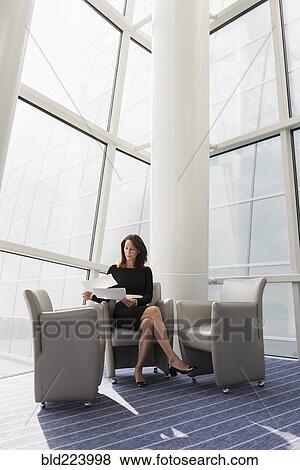 Caucasian businesswoman sitting in armchair reading paperwork View Large Photo Image Stock Photo - Caucasian businesswoman sitting in armchair reading paperwork. Fotosearch