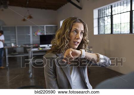 Stock Image - Caucasian businesswoman talking into smart watch in office. Fotosearch