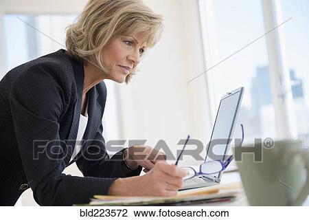 Stock Image - Caucasian businesswoman using laptop. Fotosearch