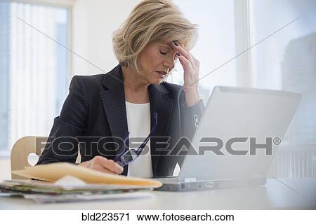 Stock Image - Caucasian businesswoman with headache using laptop. Fotosearch