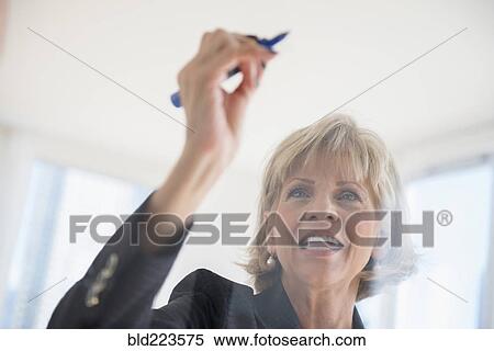 Stock Photography - Caucasian businesswoman writing on glass wall. Fotosearch