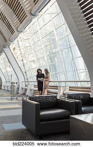 Caucasian businesswomen holding paperwork and talking View Large Photo Image Stock Photography - Caucasian businesswomen holding paperwork and talking. Fotosearch