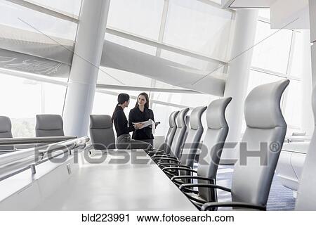Stock Image - Caucasian businesswomen talking in conference room. Fotosearch