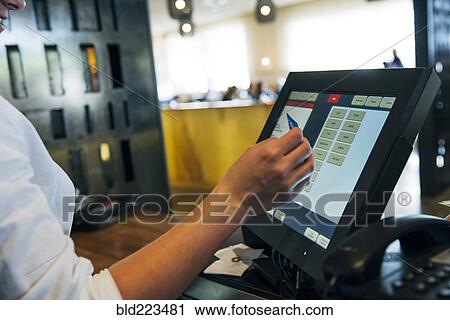 Stock Image - Caucasian cashier using touch screen to process credit card payment. Fotosearch