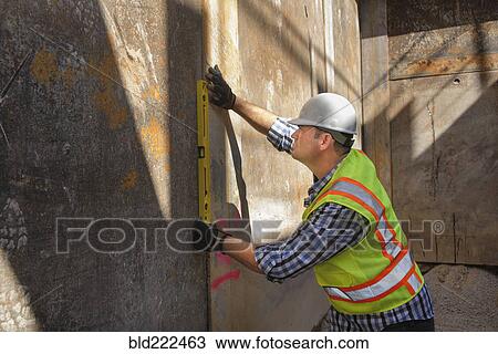 Caucasian construction worker holding level against wall View Large Photo Image Stock Image - Caucasian construction worker holding level against wall. Fotosearch