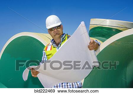 Stock Photo - Caucasian construction worker reading blueprint. Fotosearch