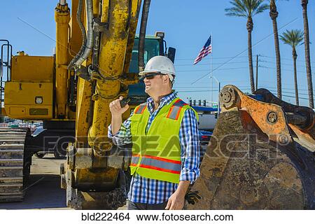 Picture - Caucasian construction worker using walkie-talkie. Fotosearch