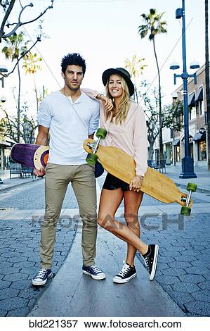 Stock Photo - Caucasian couple carrying skateboards. Fotosearch