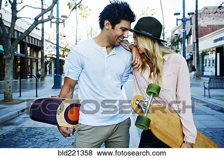 Stock Photo - Caucasian couple carrying skateboards. Fotosearch