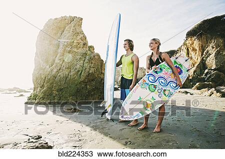 Caucasian couple carrying surfboards at beach View Large Photo Image Stock Image - Caucasian couple carrying surfboards at beach. Fotosearch